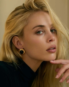 Dettaglio di orecchini vintage dorati con gemma nera indossati dalla modella