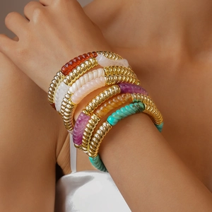Vue détaillée de bracelets dorés torsadés avec détails colorés en résine acrylique