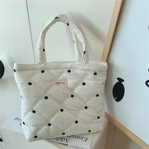 Detail of white quilted tote bag featuring black polka dots and a simple wish label
