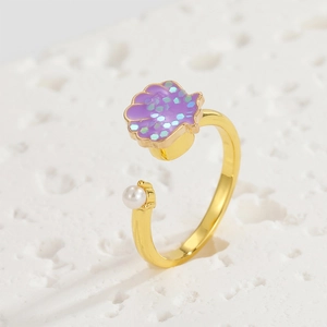 Detailed shot of an adjustable gold ring featuring a purple shell and a white pearl