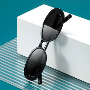 Retro oval sunglasses in black finish with dark grey lenses on minimalist white display