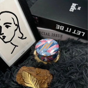 Artistic dried flower scented candle in a colorful painted metal tin on black fur background