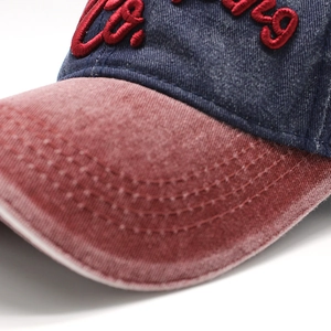 Makrodetail der Navy-Denim-Baseballkappe mit rosa gewaschenem Schirm und rotem 3D-Stick