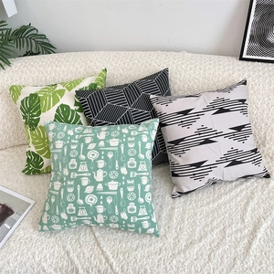 Modern cotton linen pillow covers with green leaf and geometric patterns on a white sofa