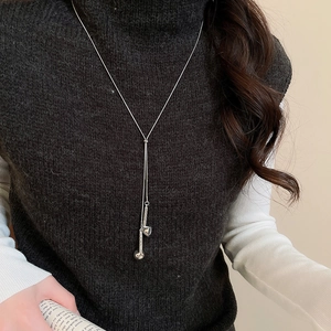 Detailed view of silver long fringe pendant necklace on a dark sweater for style