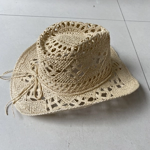 Top view of a beige straw cowboy hat with a matching bow detail on a neutral floor