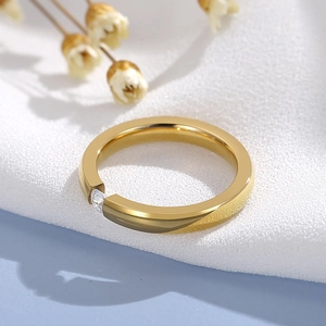 Detail view of minimalist gold ring with a sparkling round zircon on white fabric