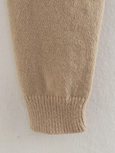 Detailed macro view of the ribbed cuff and soft knit texture of the oatmeal sweater