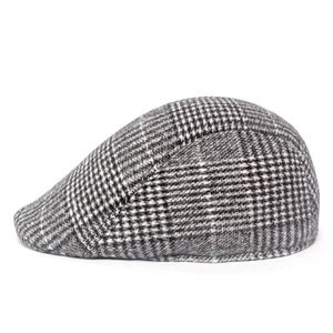 Detail of grey houndstooth wool newsboy cap showing thick textured fabric and short brim