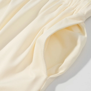 Dettaglio della vita elastica e della tasca laterale sui pantaloni in maglia color crema