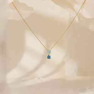Detail of 18K gold plated titanium necklace with round and teardrop blue gemstones