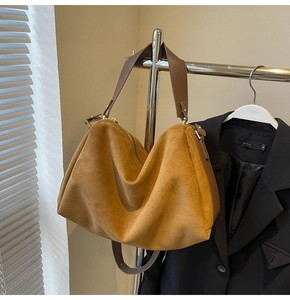Close-up of caramel suede tote bag with brown leather strap on a metal hanger