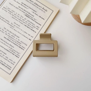 Close-up of a matte khaki rectangular hair claw clip on an open English book page