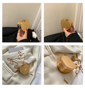 Detail of a shiny gold heart-shaped mini bag with fine metal chain and mirror finish