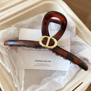 Détail de la pince à cheveux écaille avec emblème de fleur dorée sur fond de papier
