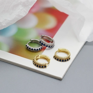 Macro shot of gold and silver plated earrings with double row blue stones and white diamonds