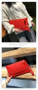 Detail van rode envelop-clutch met kiezeltextuur, gouden studs en een polsbandje