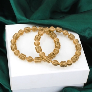 Detail of two gold spiral-textured bangle bracelets on a jewelry box with silk