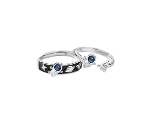 Close-up of minimalist astronaut couple rings set with black enamel and blue crystal detail