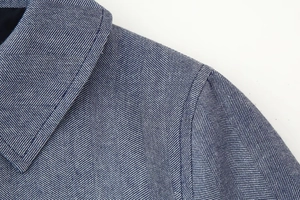 Nahaufnahme von blau-weißem Fischgrätmuster mit feiner Naht an der Blazer-Schulter