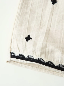 Close-up of geometric black embroidery on beige linen fabric texture and hem detail