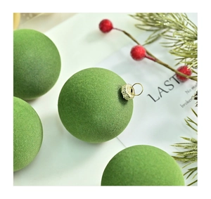 Close-up of green flocked Christmas ball with gold metal cap and festive pine decor