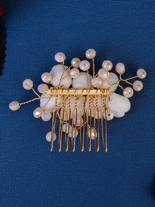 Detailed macro view of handmade floral hair comb with peach beads and white resin petals
