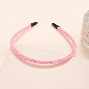 Detailed view of pink glitter headband with protective black tips on smooth surface
