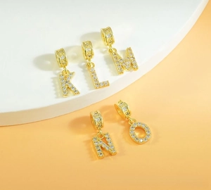 Detailed view of gold-plated alphabet charms K-O with micro-pave cubic zirconia