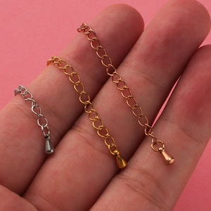 Detailed macro view of mirror polished water drop pendants on stainless steel extension chains