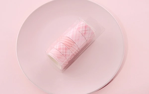 Detail view of 5 rolls of pink checkered washi tape in a clear box on a ceramic tray