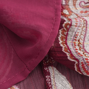 Détail macro du tissu bordeaux avec fil doré et motifs de textures paisley floraux