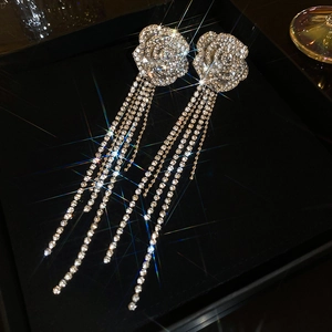 Detailed view of silver flower tassel earrings with crystals in a luxury black jewelry box