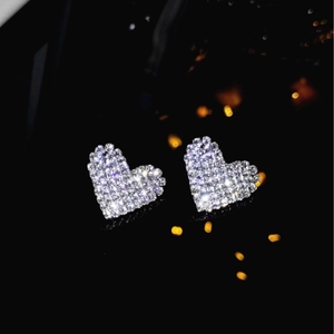 Sparkling silver heart stud earrings with pavé crystals on a black reflective background