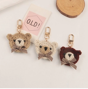 Detail of handcrafted woven bear keychains in beige, cream and brown with plaid bows