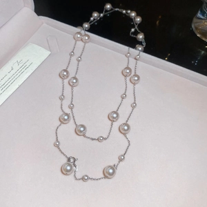 Detail of layered French rose pearl necklace on light pink jewelry box background