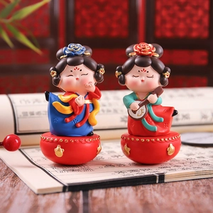 Detailed view of two resin Chinese Tang dynasty style tumbler dolls on a desk