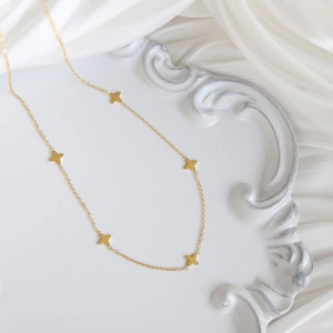 Elegant gold clover necklace with star pendants on textured white decorative plate