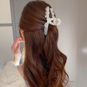 Vue arrière d'un modèle portant une pince à cheveux blanc nacré à bords plissés
