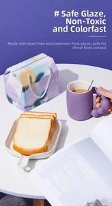 Purple ceramic mug with unique ball handle and colorful gift box in high-angle shot