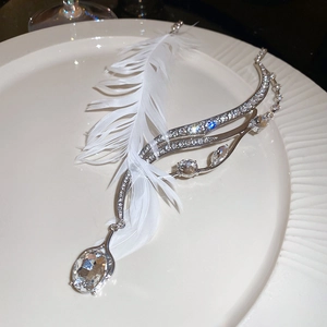 Détail du collier plume en argent orné de cristaux brillants sur plat en porcelaine
