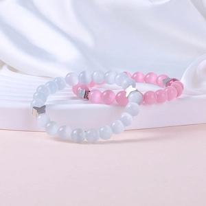 Pink and white cat eye beaded bracelet with metal butterfly charm on silk fabric