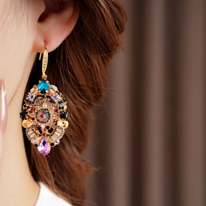 Close-up of vintage gold earrings with colorful crystals worn by a female model