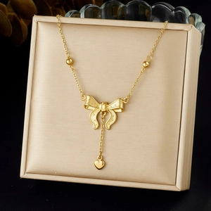 Détail d'un collier nœud doré avec pendentif cœur exposé sur un coffret à bijoux