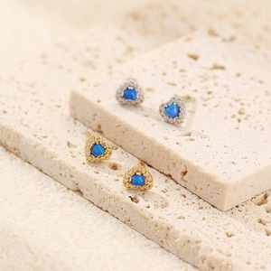 Macro shot of heart-shaped earrings with blue opal and small crystals on stone
