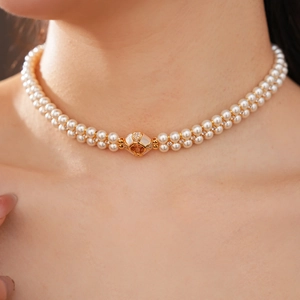 Gros plan d'un collier de perles double épaisseur avec pendentif doré sur le cou