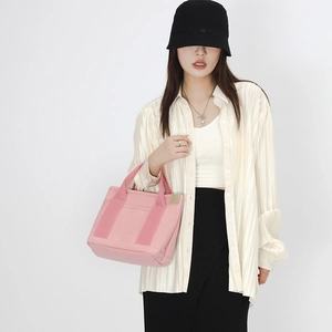 Detailed view of pink canvas tote bag carried by a model in casual white outfit