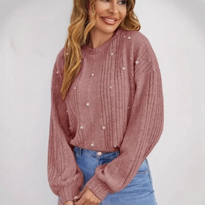 Détail des perles décoratives sur le pull en maille rose avec manches bouffantes