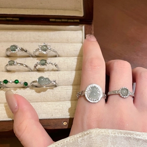Detailed view of silver rings featuring green gourd jade and zircon in a luxury jewelry box