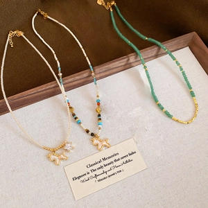 Macro shot of beaded necklaces with shell puppy pendants in a rustic wooden tray